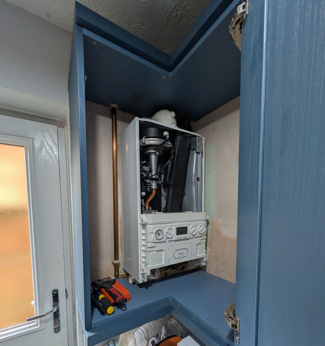 Ideal boiler in a kitchen cupboard with the casing off, part way through a service